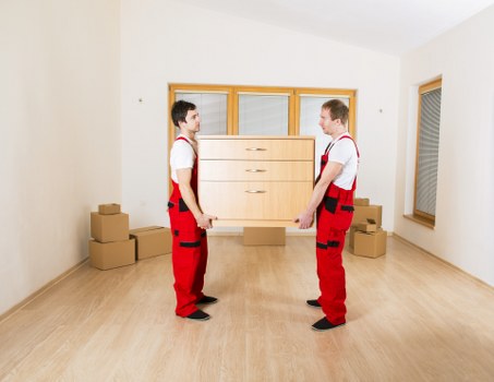 Removals team handling furniture and boxes in a South London flat move